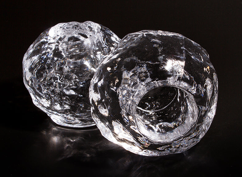 Two textured, clear glass sphere tea light candle holders sat against a black background.