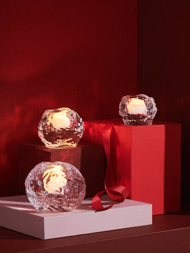 Three textured glass sphere tea light candleholders displayed on different sized decorative boxes against a red background.