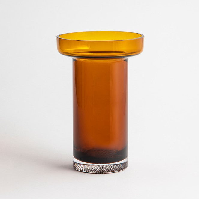 A brown glass vase with a tall cylinder shape that widens into a wide flat cylinder at the top sat against a white background.