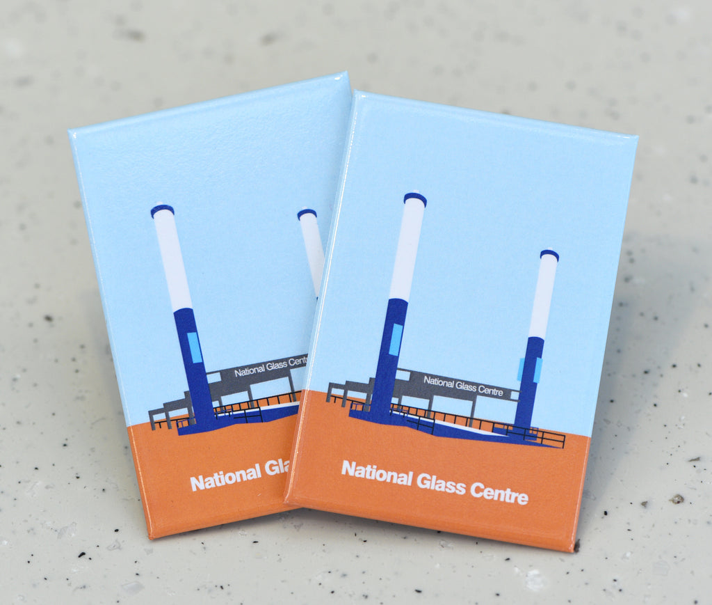 Two flat rectangular magnets featuring a graphic illustration of a building with two thin columns on either side in blue grey and white. Along the orange floor, white bold text reads "National Glass Centre"